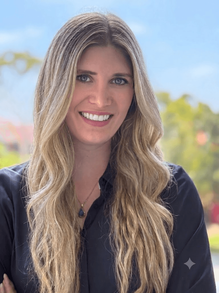 Rebecca Share-Howard smiling in a navy blouse against a softly blurred outdoor background